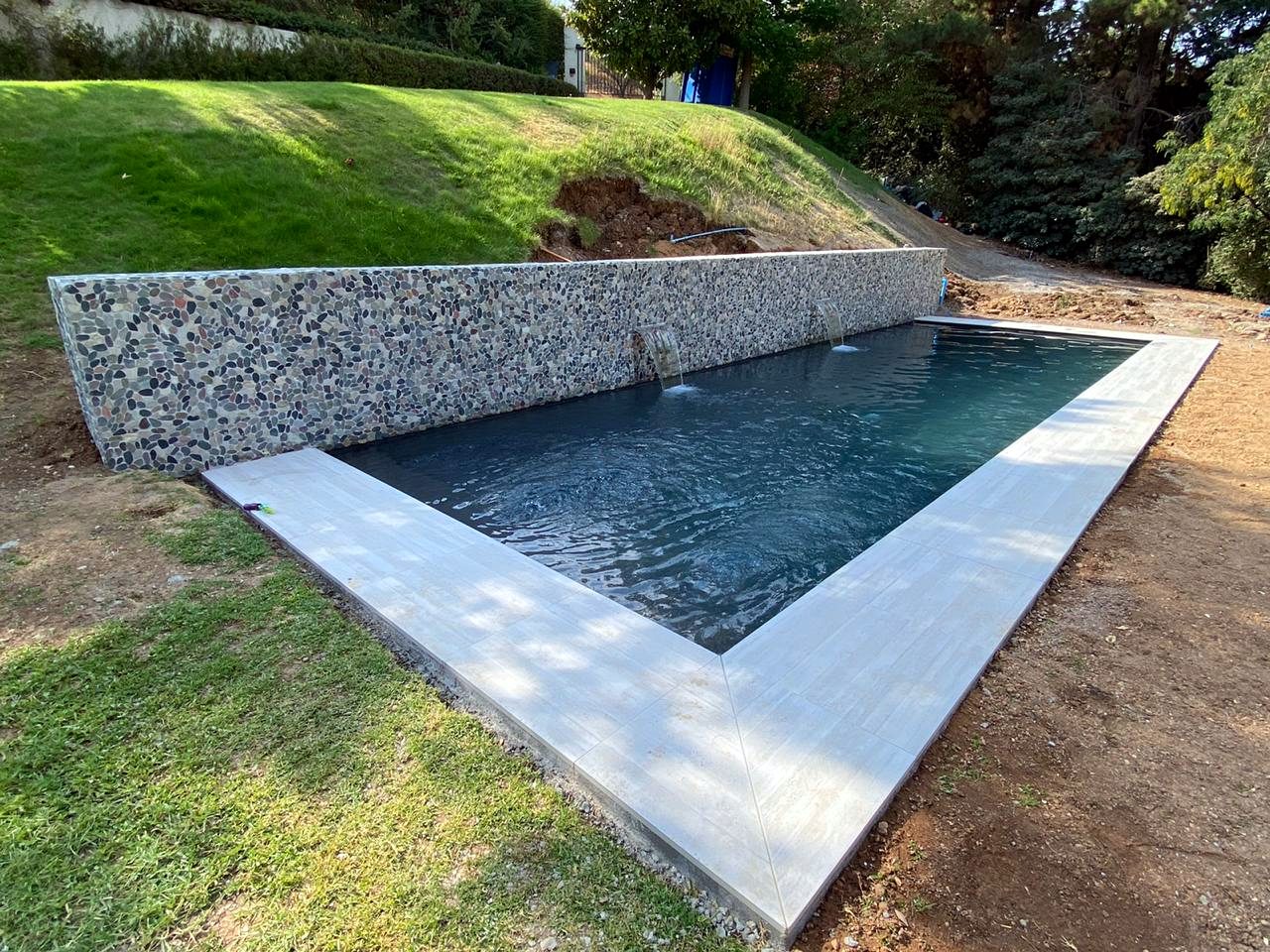 Piscina con muro de piedra de río y cascadas